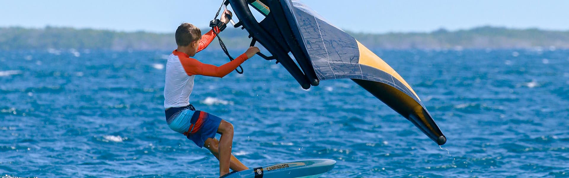 A young person enjoys kite surfing on a sunny day at sea.