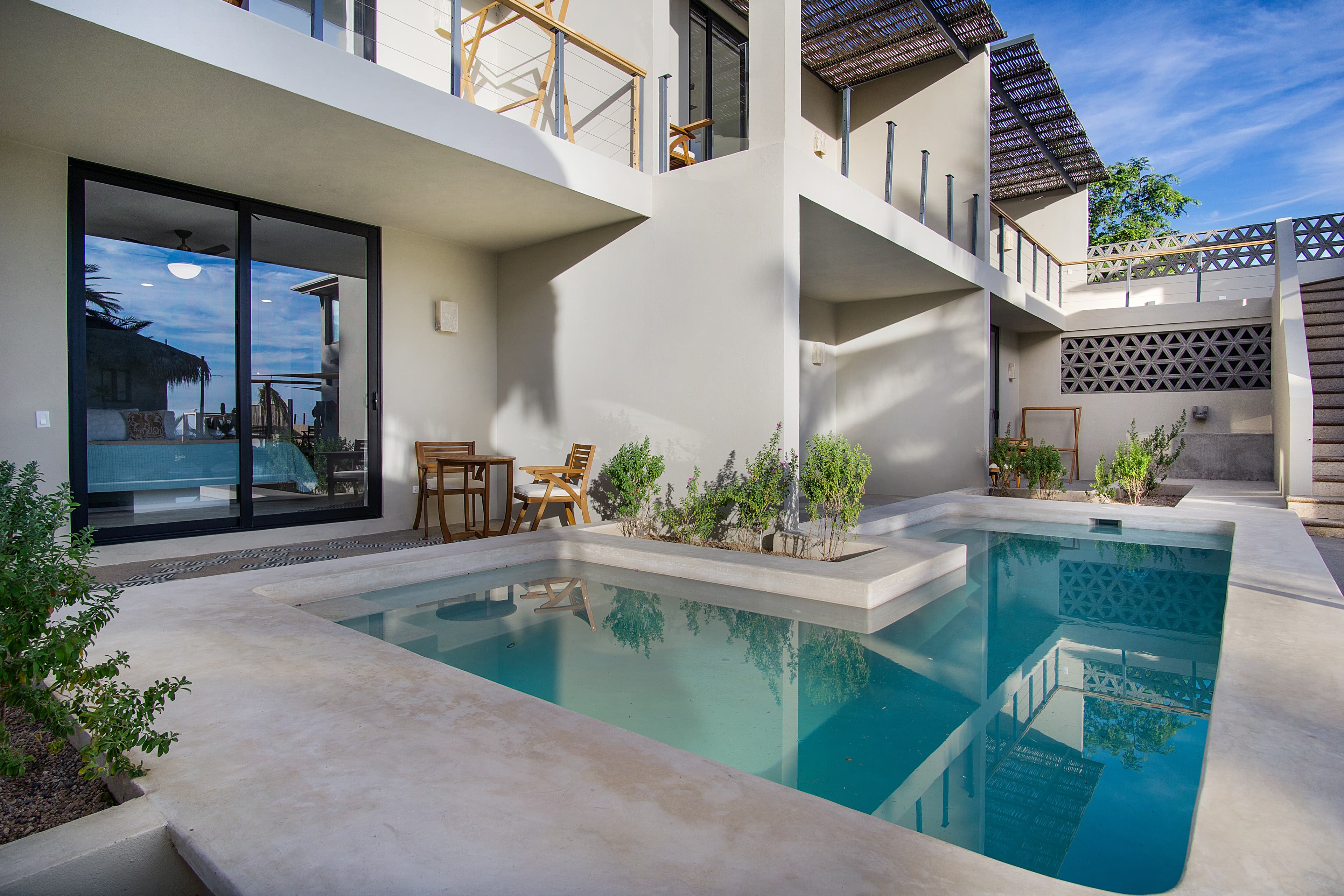 A modern outdoor space featuring two small pools surrounded by plants and contemporary architecture.