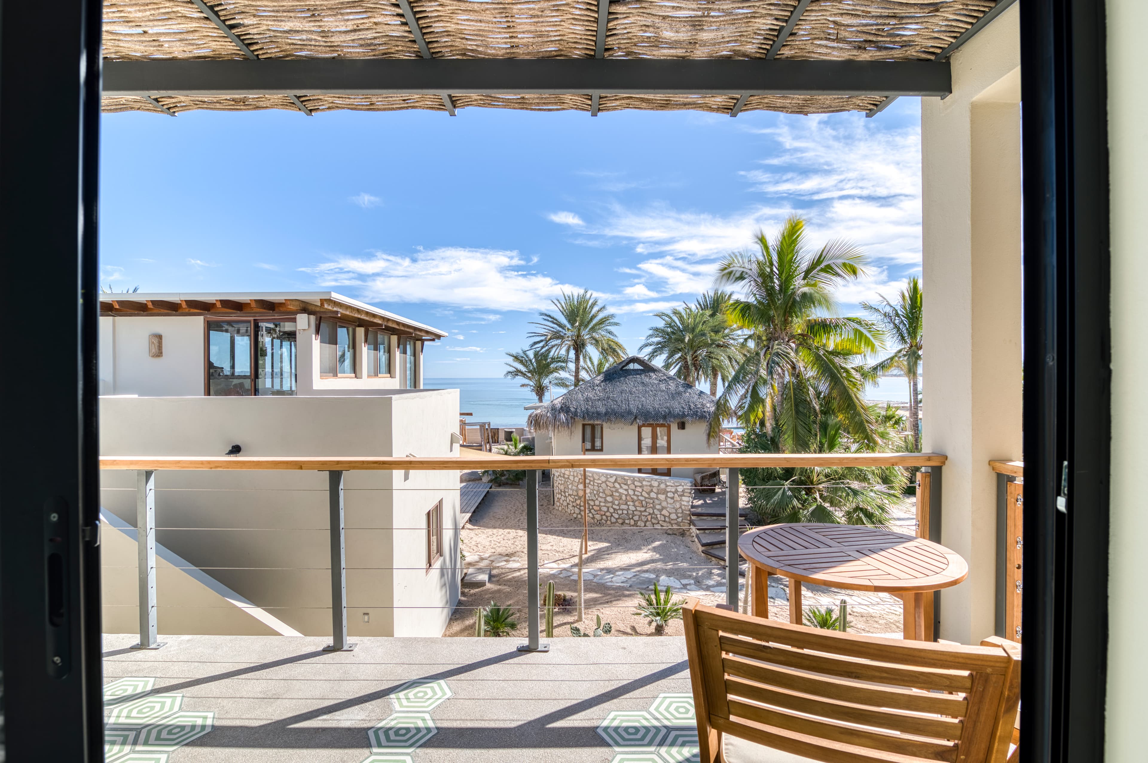 View from a balcony overlooking palm trees and a coastal landscape.