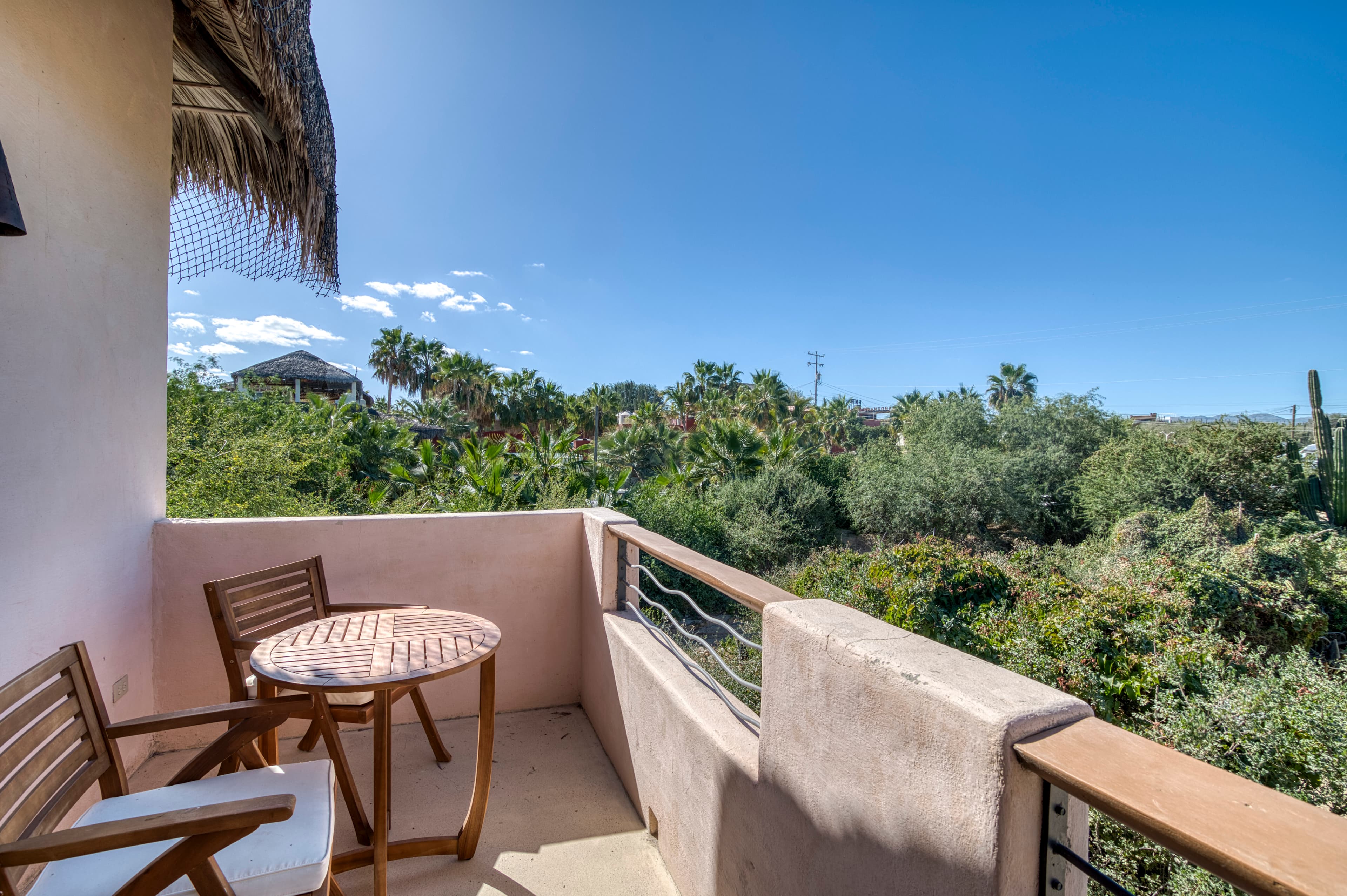 Balcony with a round table and two chairs overlooking a lush green landscape.