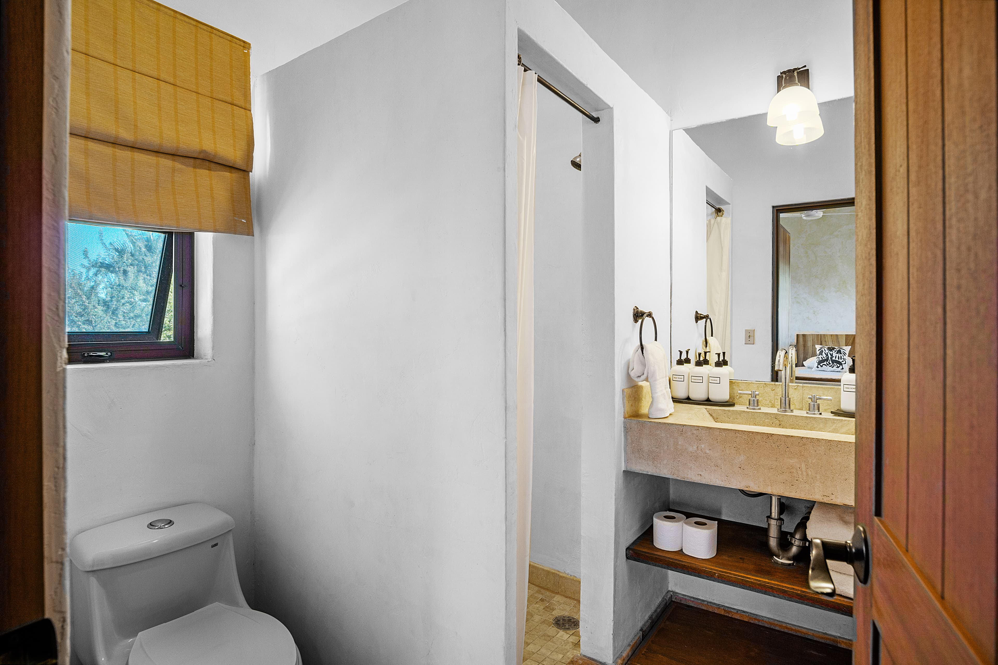 A compact bathroom featuring a toilet, sink with countertop, and a shower area.