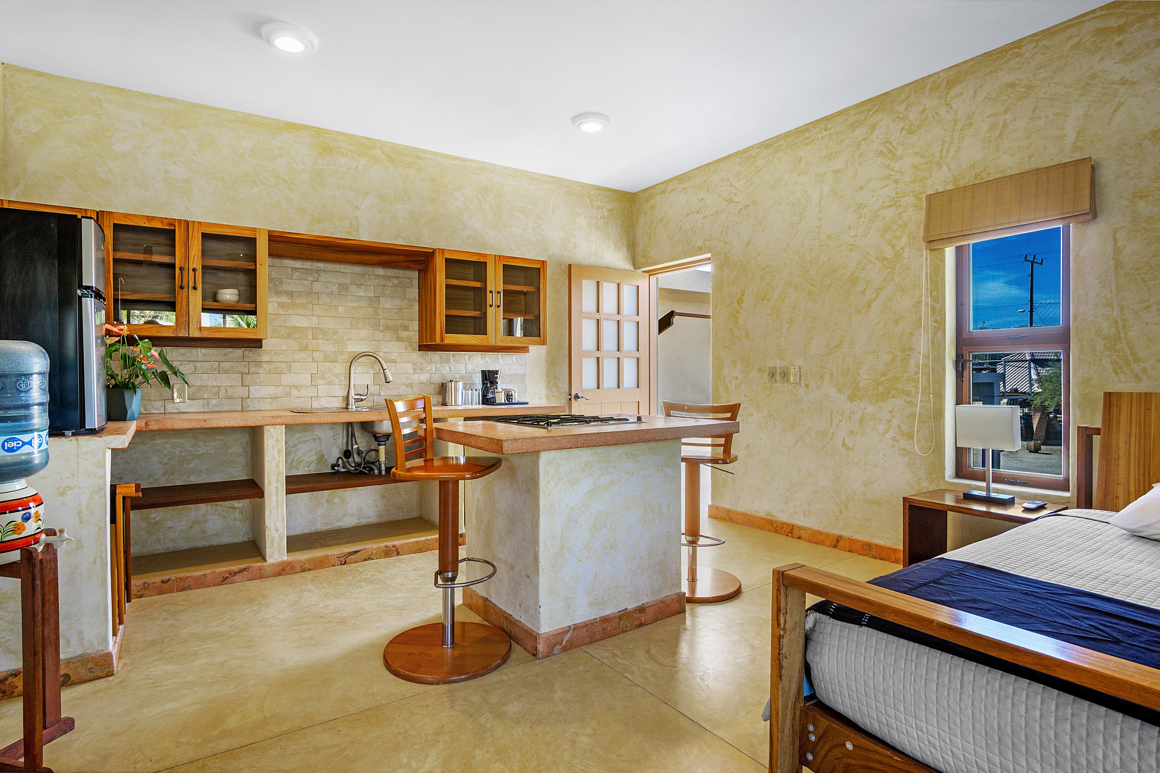 A modern, open-concept kitchen and bedroom with natural light and minimalist décor.