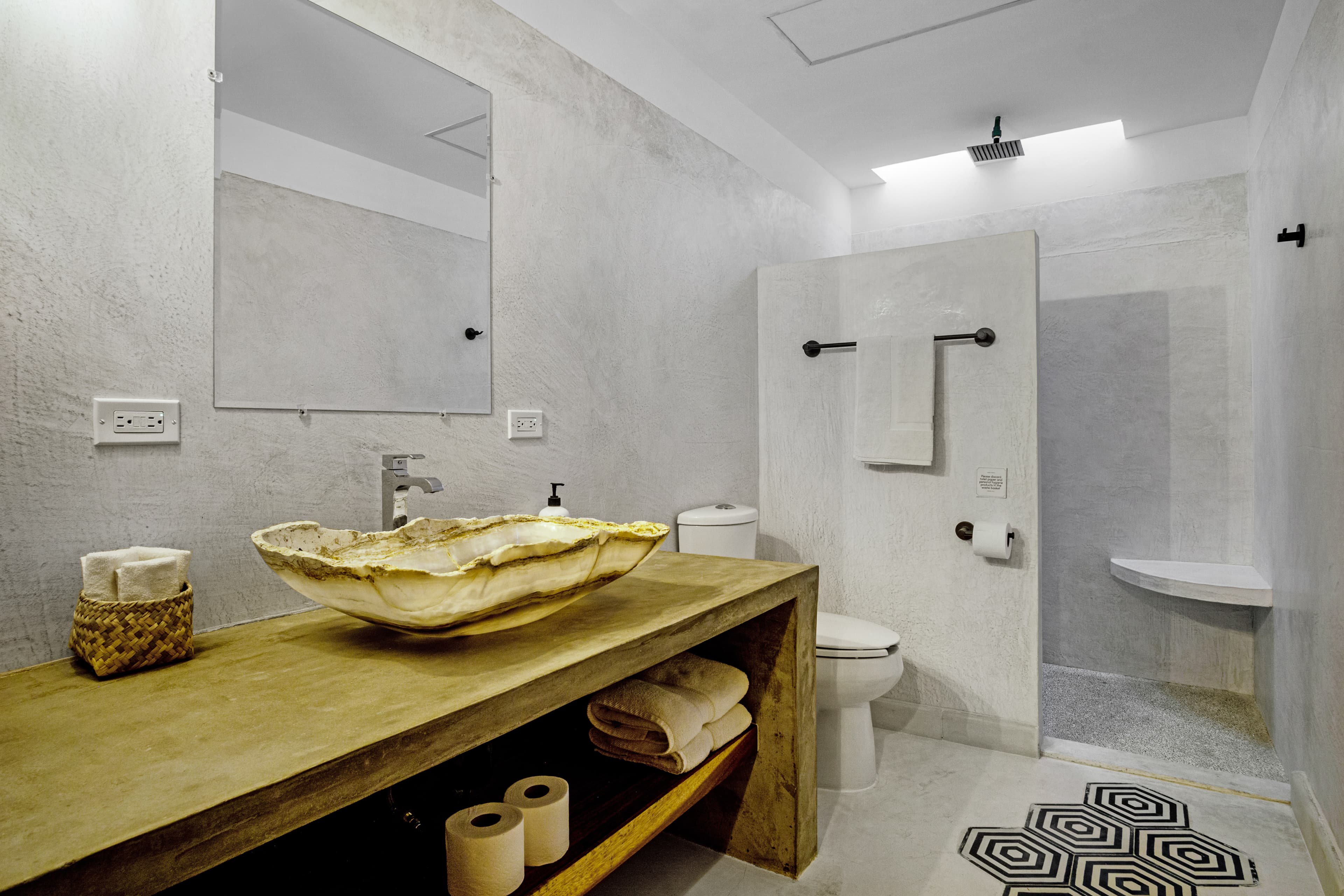 Modern bathroom featuring a sleek stone sink, minimalist decor, and a glass shower enclosure.