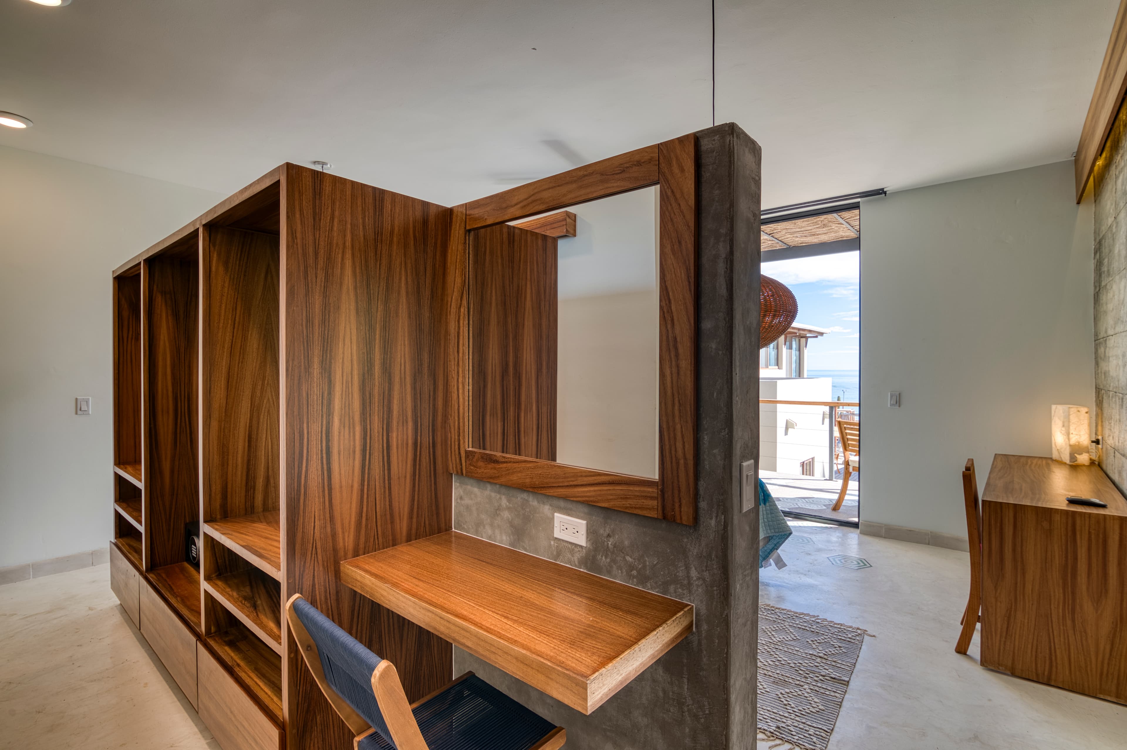 A modern workspace featuring a wood-accented desk and shelving unit with a view of the outdoors.