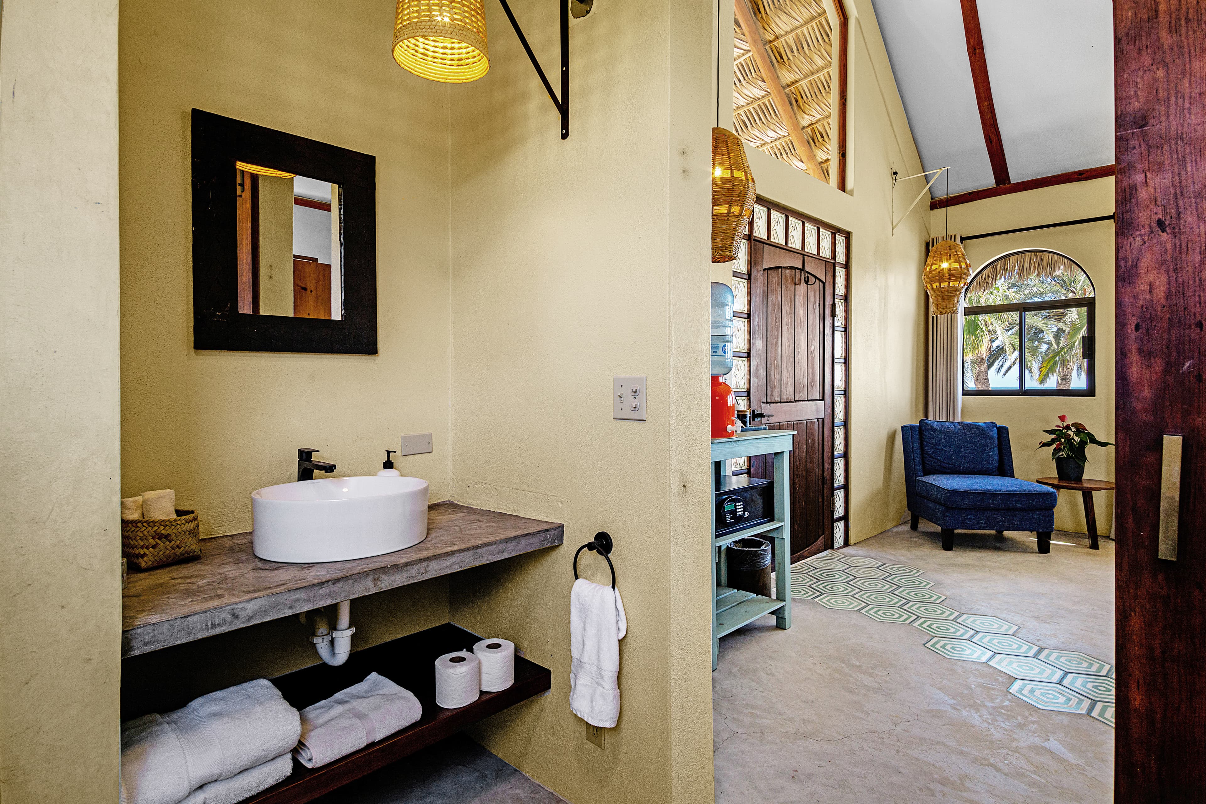 A stylish bathroom featuring a modern sink, towels, and a sitting area with a blue chair.