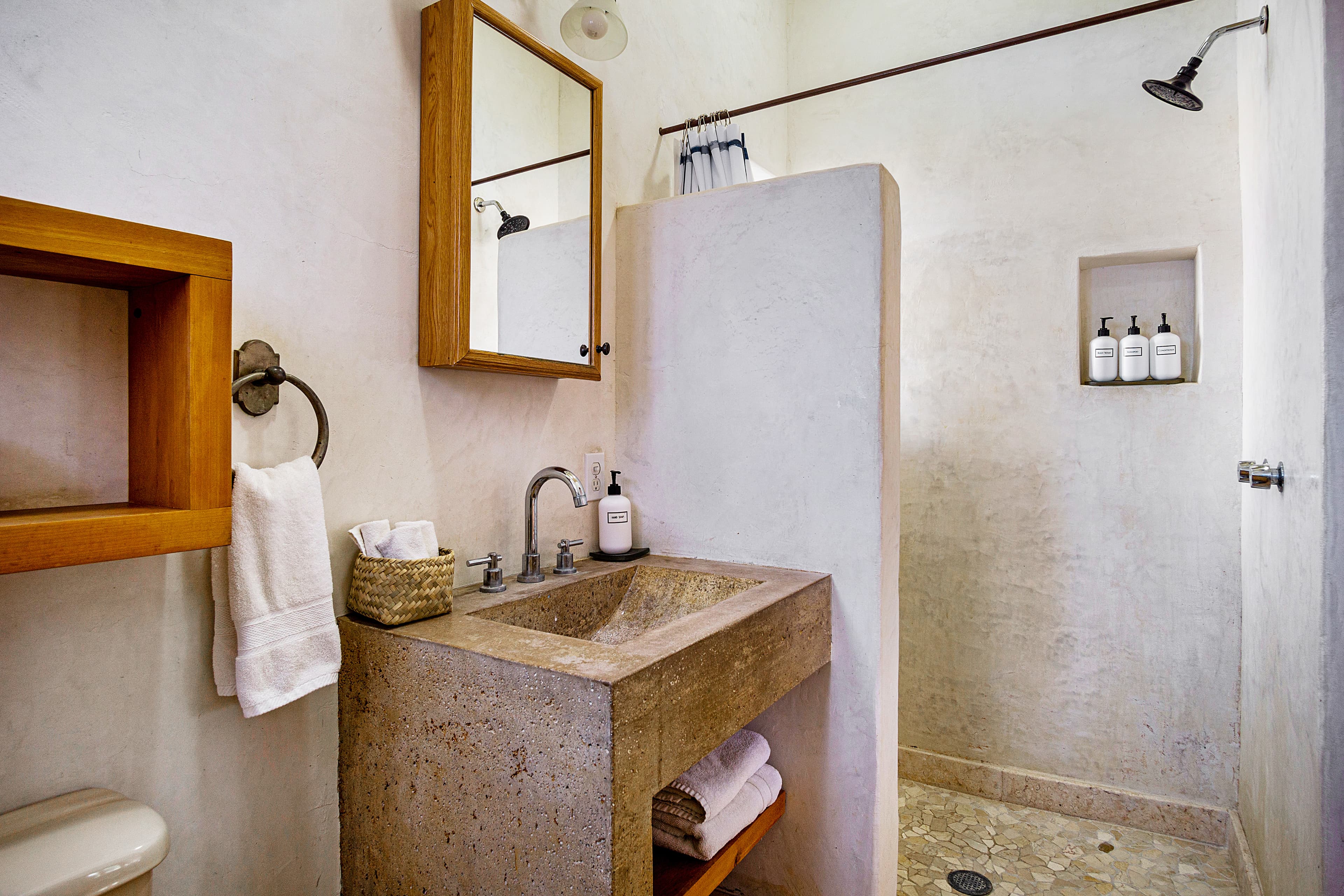 A modern bathroom featuring a stone sink, wooden accents, and a separate shower area.