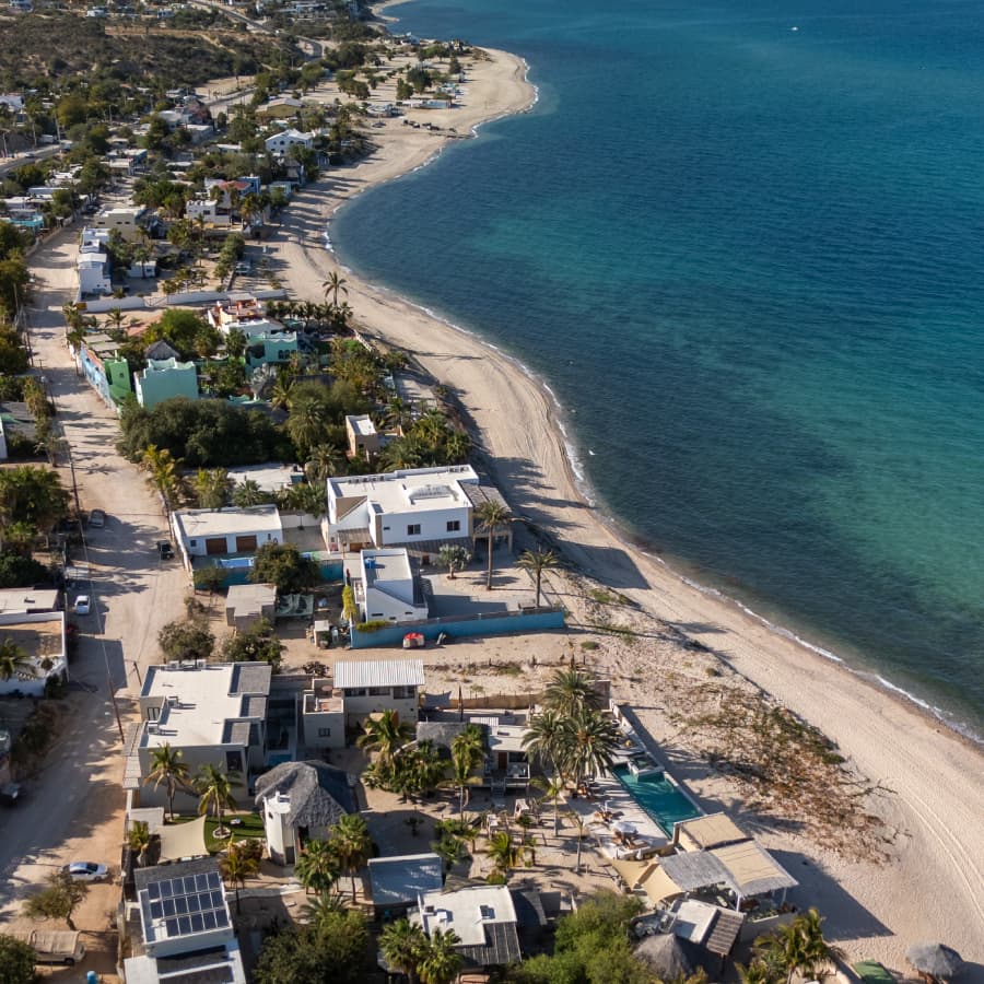 Aerial view of a coastal village with white sandy beaches and turquoise water.