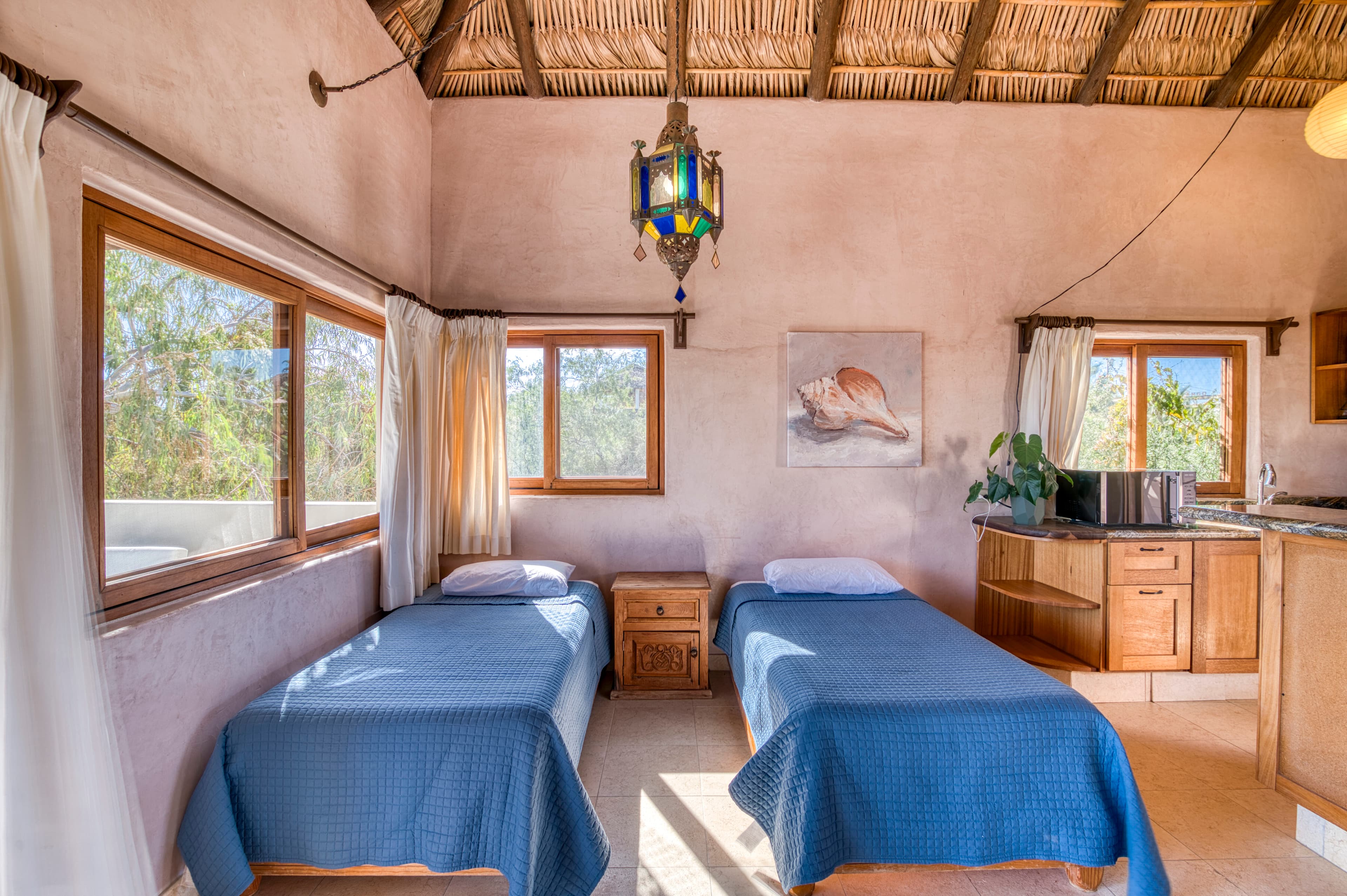 A cozy bedroom featuring two twin beds, wooden furniture, and large windows with natural light.