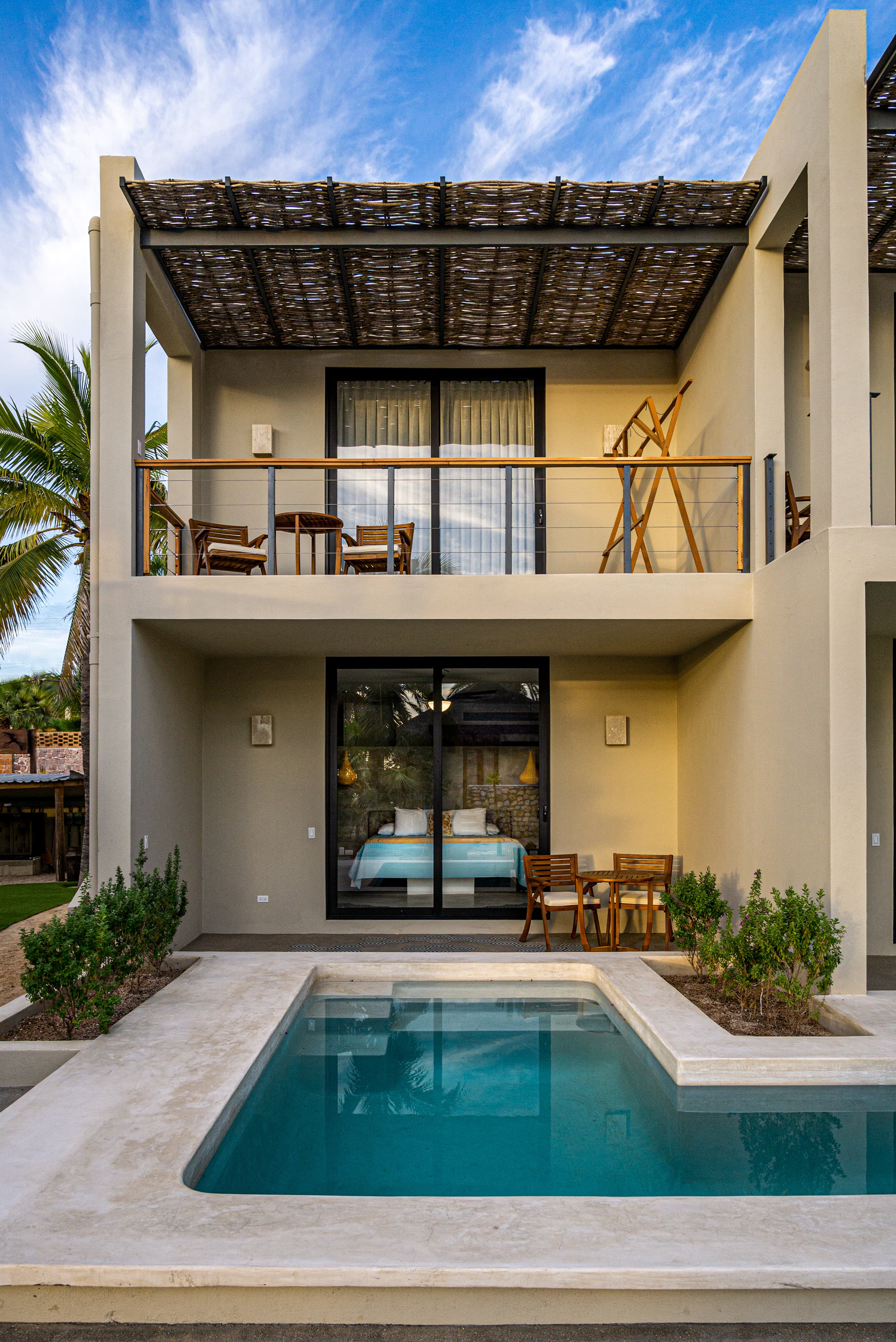 A modern villa with a private pool and balcony surrounded by lush greenery.