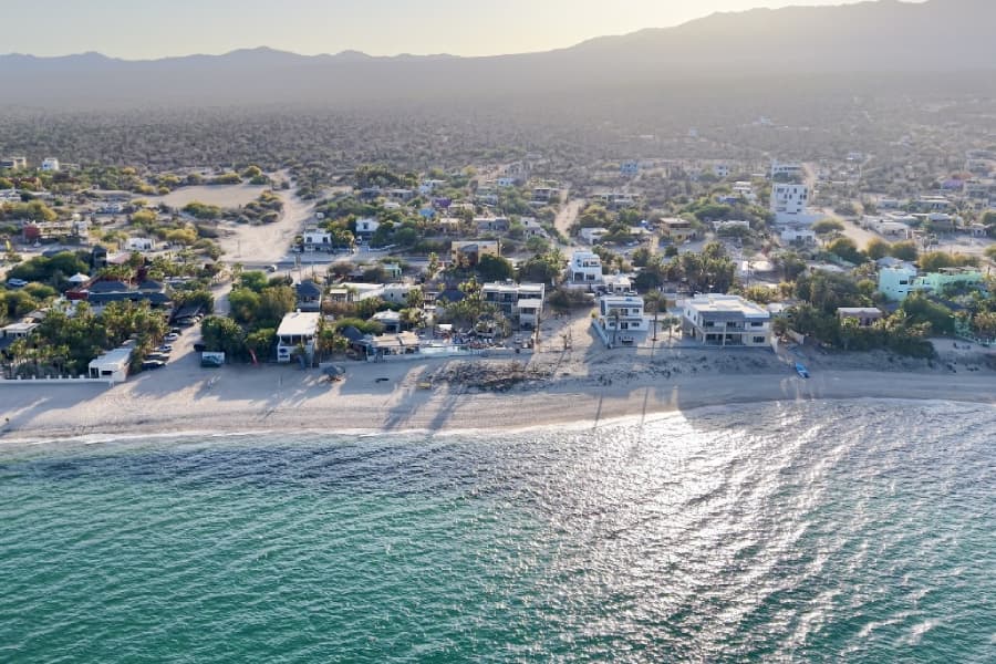Aerial view of a coastal town with sandy beaches and scattered residential buildings.