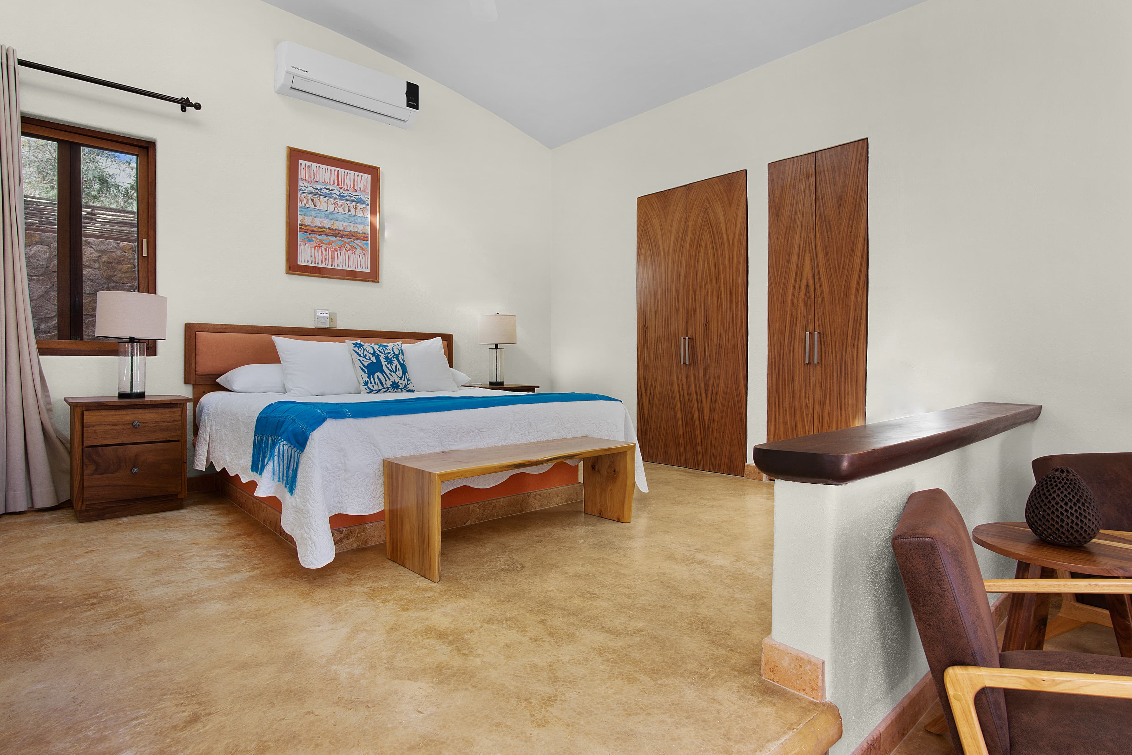 A cozy bedroom featuring a bed with a blue and white blanket, wooden furniture, and warm lighting.