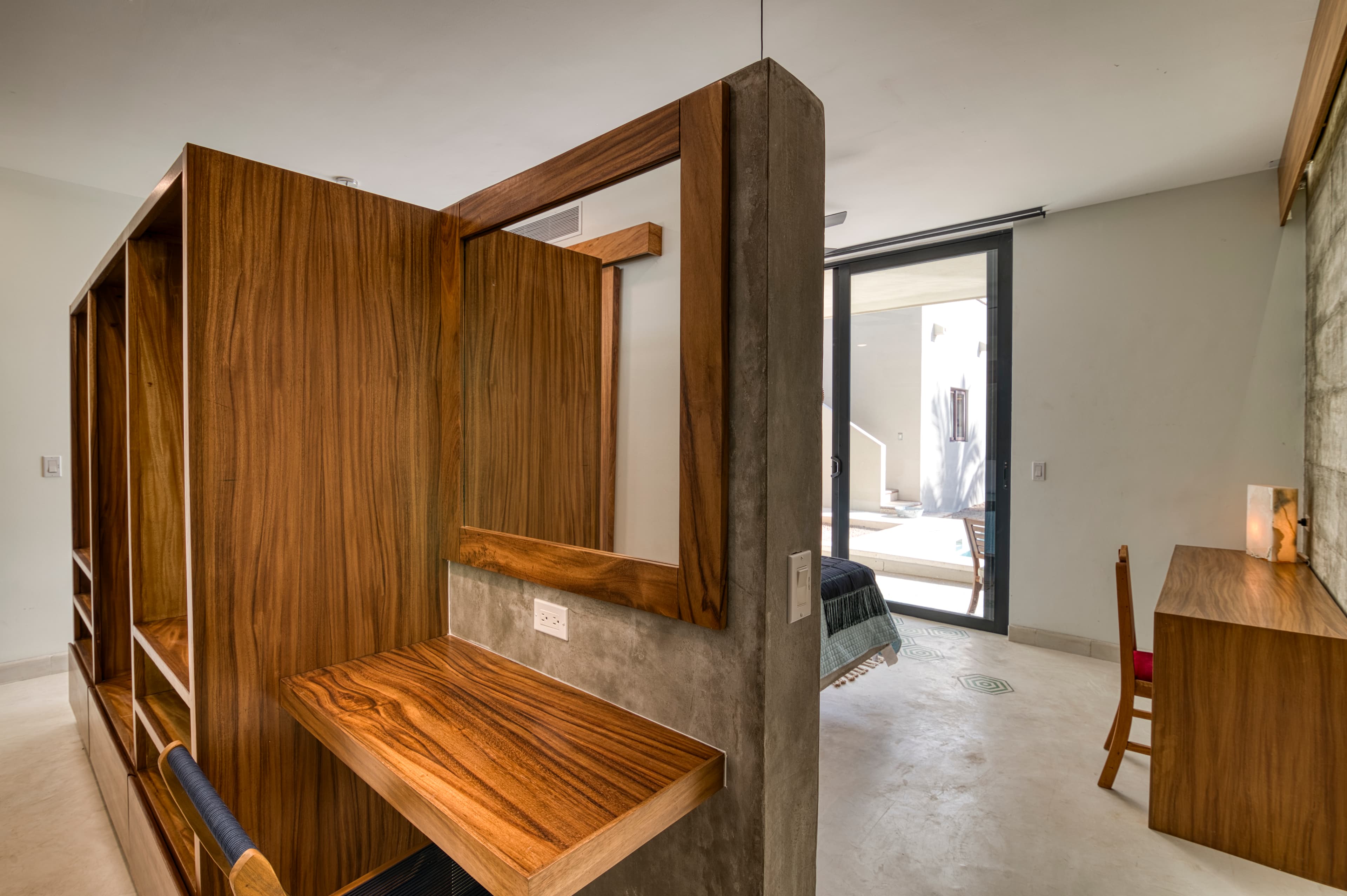 A modern room featuring wooden shelving, a desk, and large windows leading to an outdoor space.