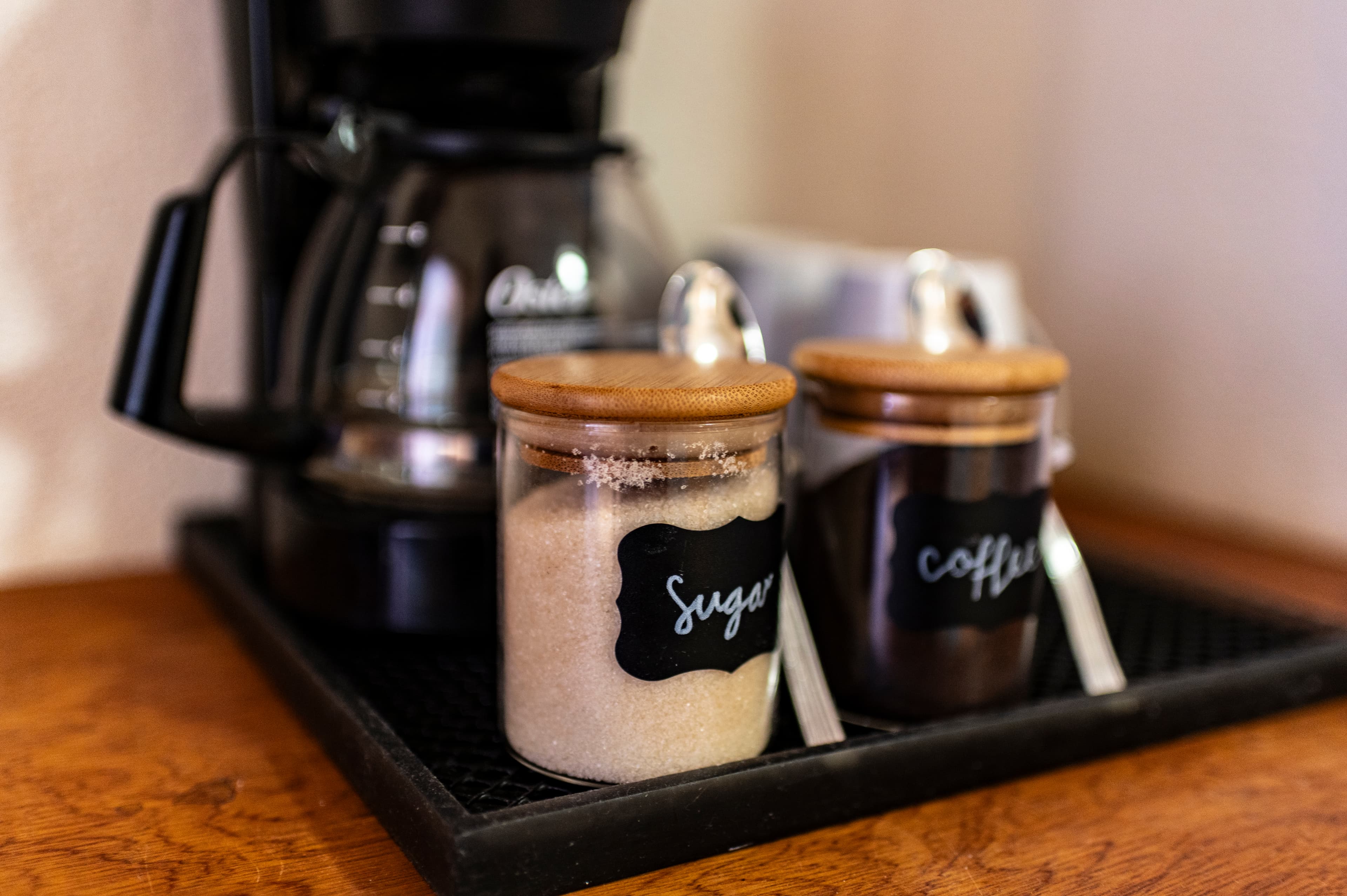 A coffee maker with glass containers labeled "sugar" and "coffee" on a wooden surface.
