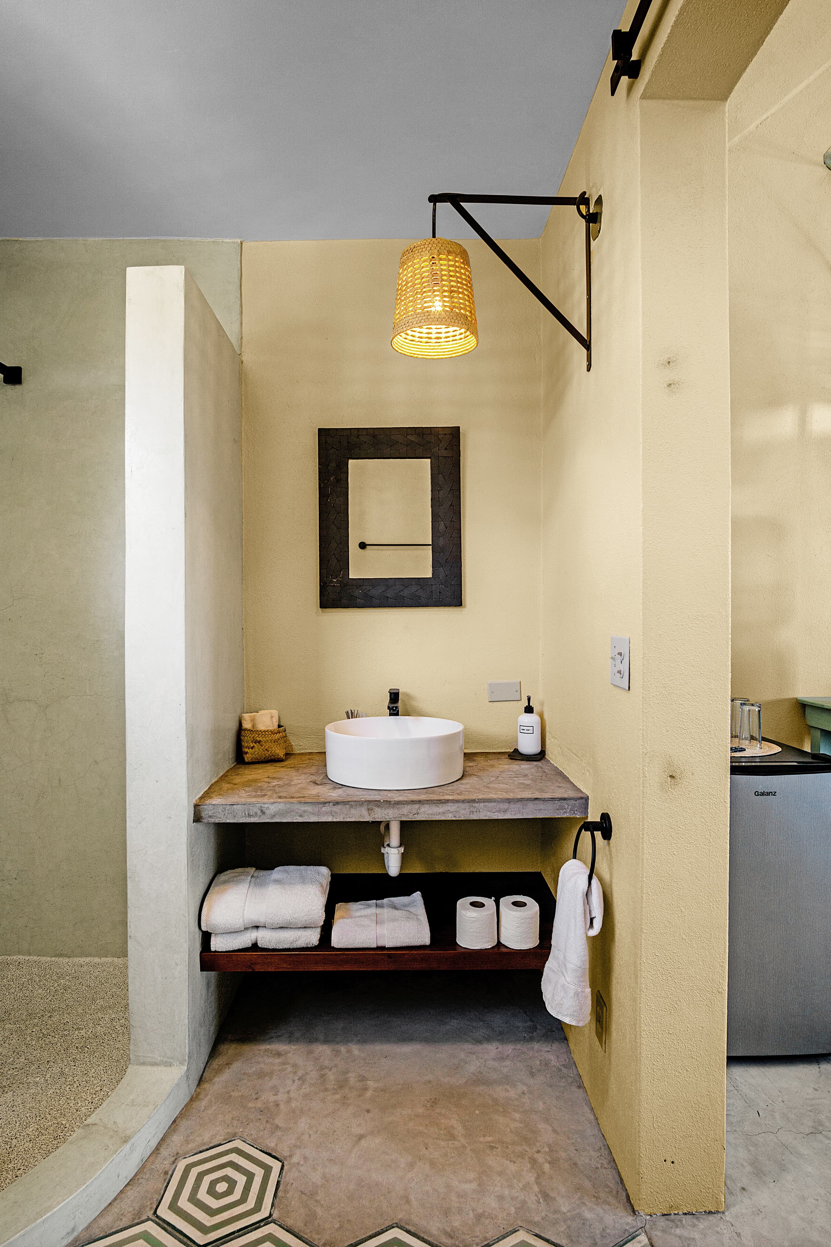 A modern bathroom featuring a circular sink, towels, and a decorative hanging light.