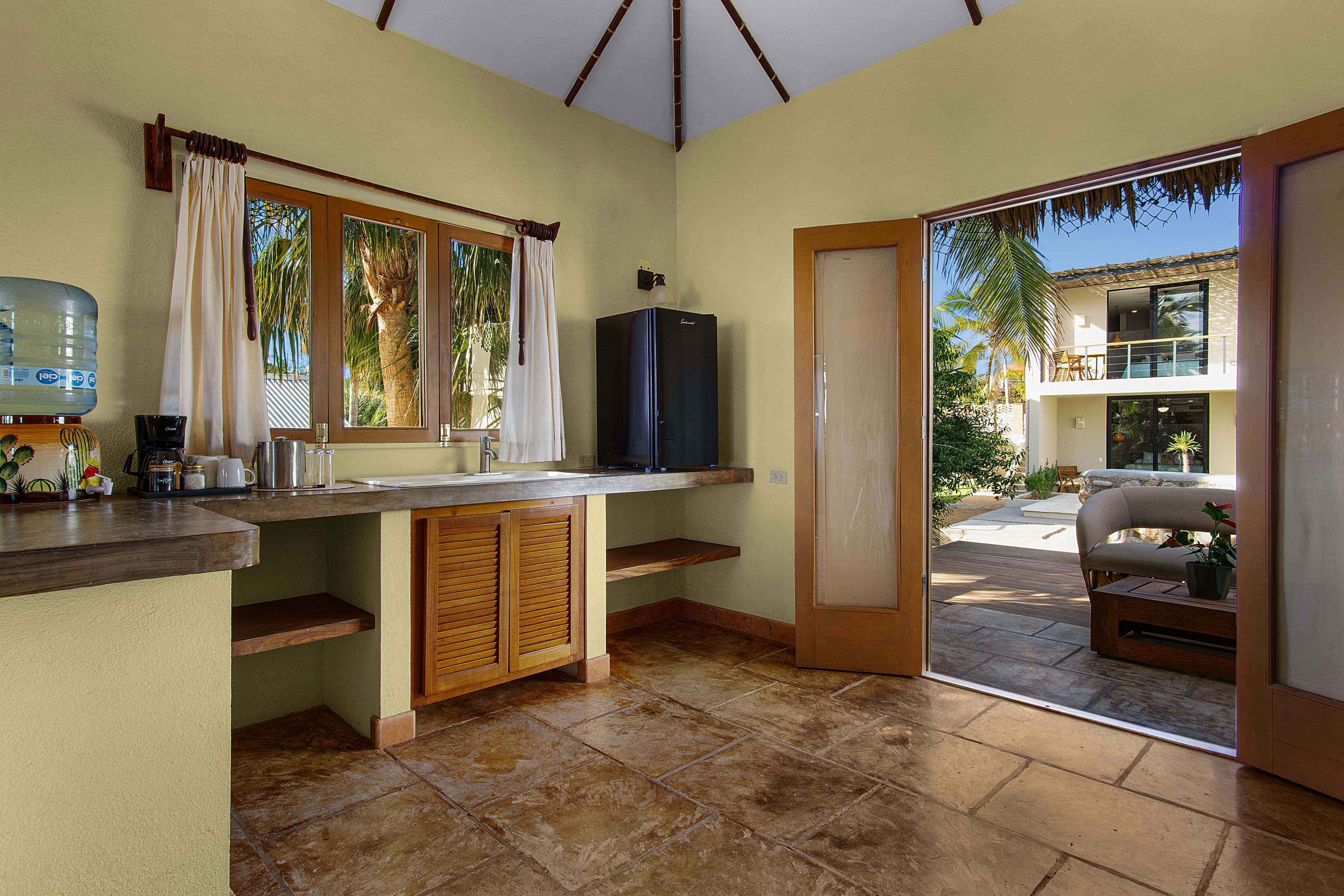 Bright kitchen with a view of a patio and palm trees outside.