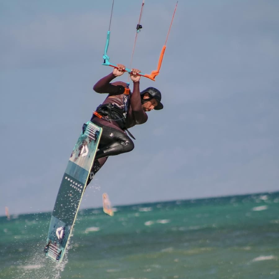 A kitesurfer performs a jump above the water.