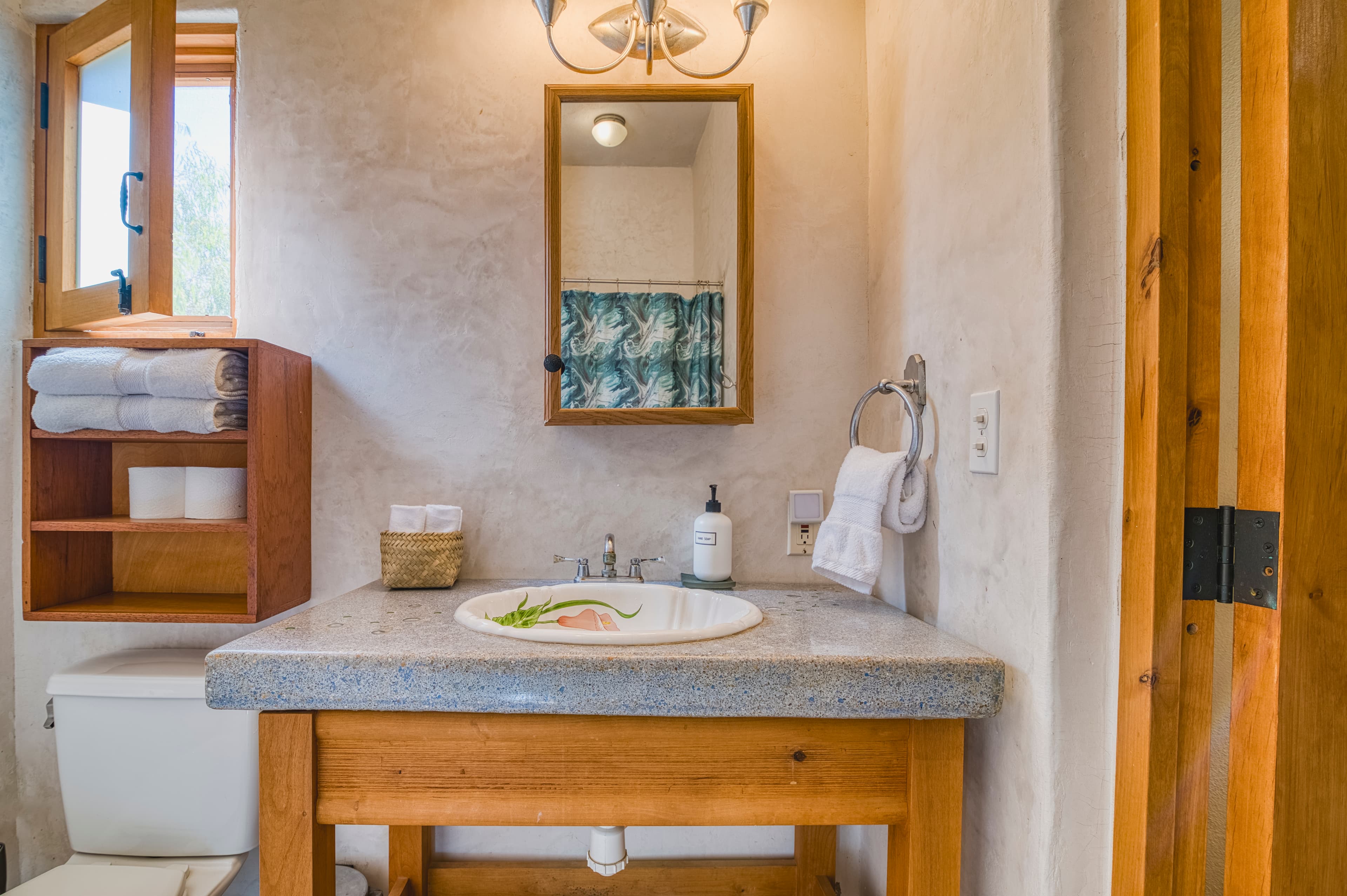 A rustic bathroom featuring a stone sink, wooden cabinetry, and natural lighting.