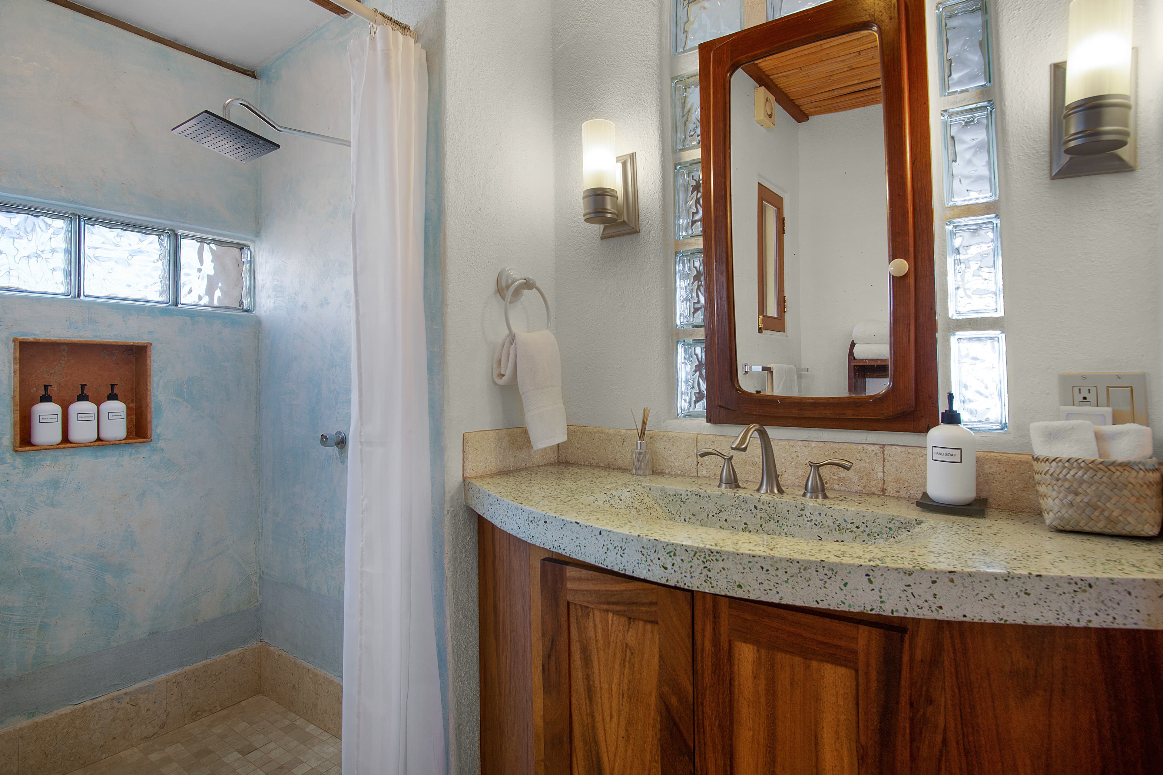 A modern bathroom featuring a shower stall, a stone countertop with sink, and decorative accents.