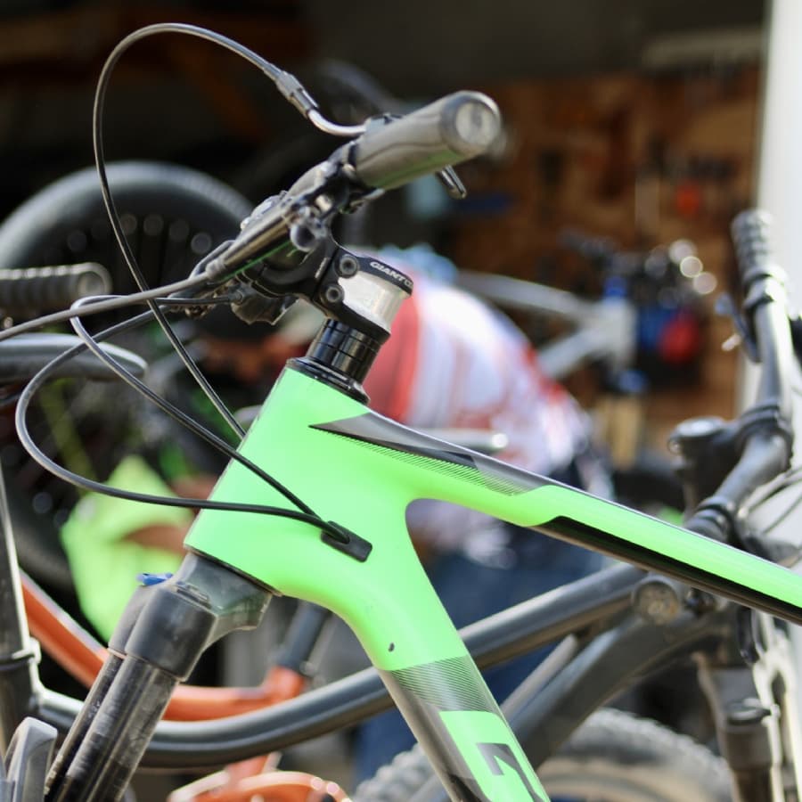 A close-up of a green mountain bike's handlebars and frame with a blurred figure in the background.