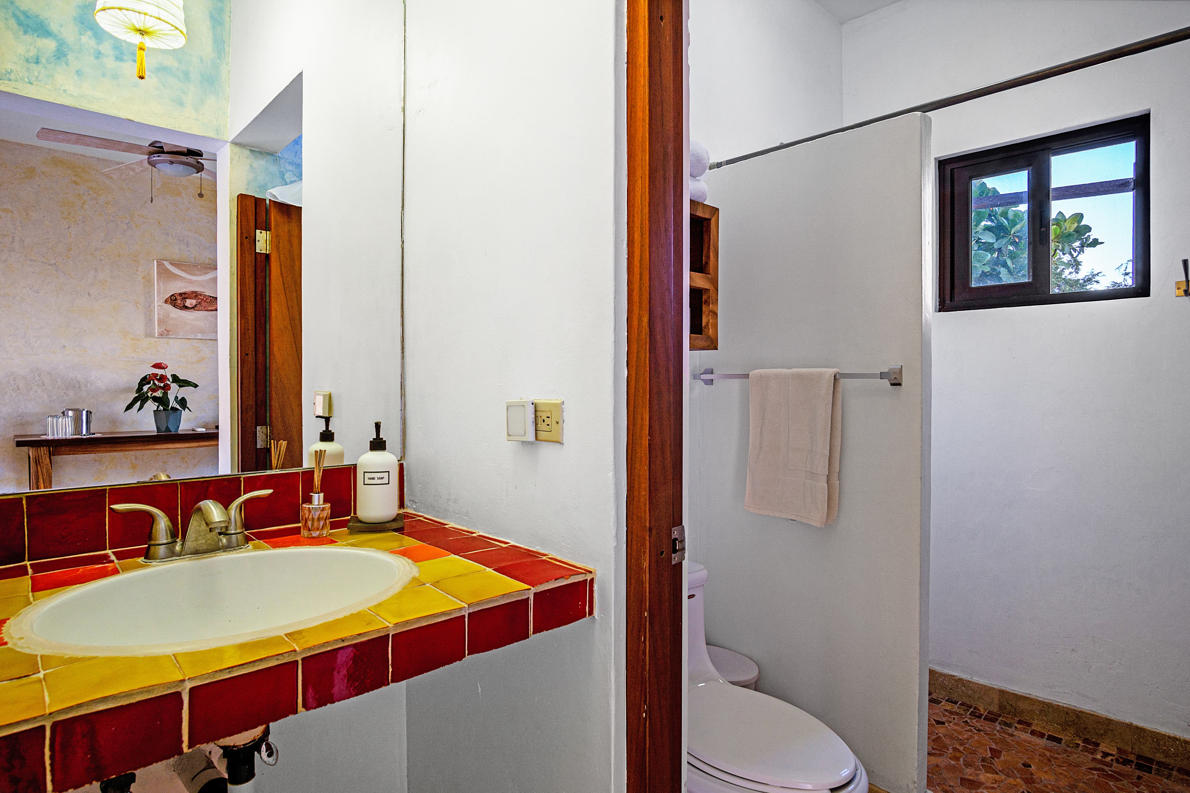 Bright bathroom featuring a red-tiled sink, shower, and modern fixtures.